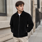 Man styling the black men's corduroy jacket on a quiet US city street.