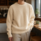 Man wearing the light yellow men's crewneck sweater in a softly lit US cafe.